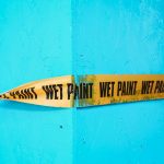 a yellow and black sign on a blue wall